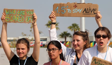 Climate activists gather holding up 1.5 C sign.
