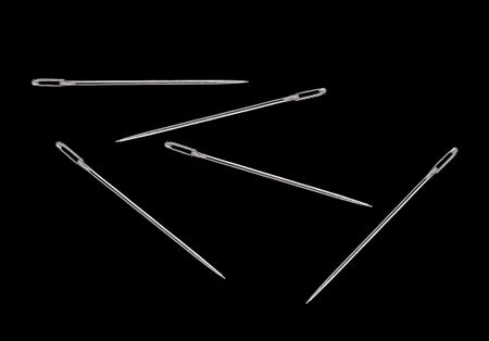 Five sewing needles on black background