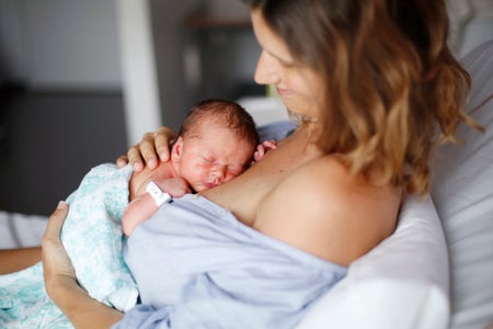 Woman in hospital holding newborn baby.