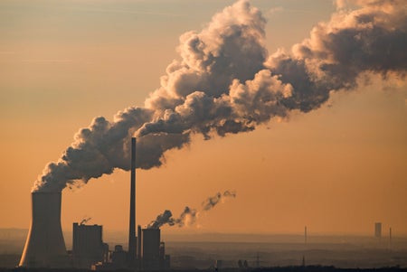 Steam and exhaust rise from the power plant at dusk.