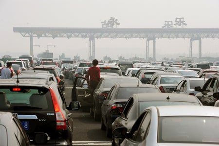 Chinese motorists get out of their cars to check on a massive traffic jam at a toll booth on the outskirts of Beijing on October 2, 2010