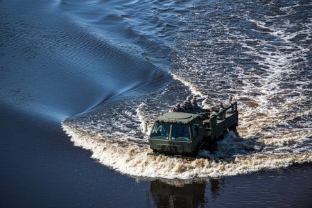 U.S Air Force airmen drive a vehicle through floodwaters