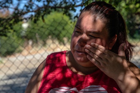 Woman in red shirt wipes sweat from face